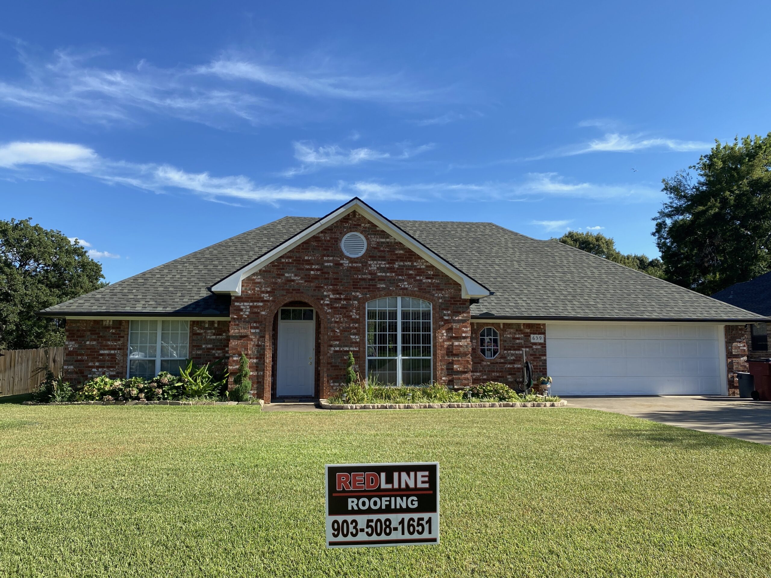 New charcoal shingle roof replacement on brick home with Redline Roofing yard sign, Tyler TX