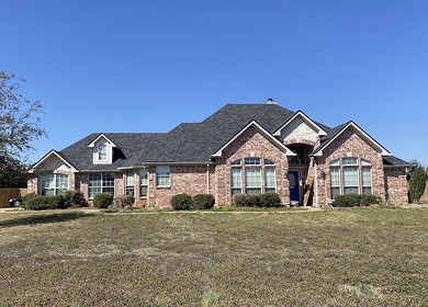 Large brick home with new dark shingle roof installation near Tyler, TX