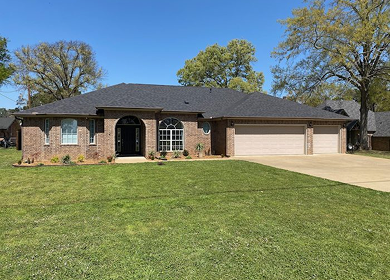 Brick home with new shingle roof replacement, American flag, sunny day near Tyler TX