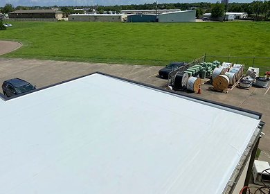 Aerial view of completed white TPO flat roof installation on commercial building in East Texas