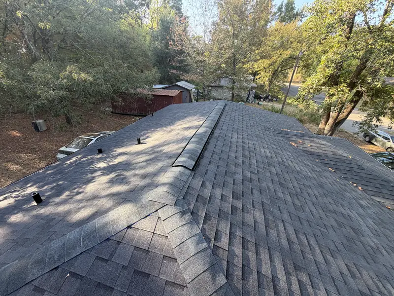 New charcoal shingle roof with ridge vent and pipe boots installed on a Gladewater, TX home